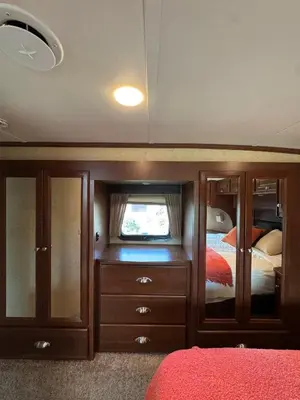 a bedroom with a dresser and a tv and a bed at Prairie Junction Resort - Furnished RV Apartments in Stettler