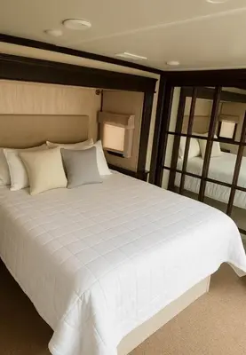 a large white bed in a room with a mirror at Prairie Junction Resort - Furnished RV Apartments in Stettler