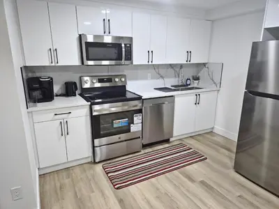 a kitchen with stainless steel appliances and white cabinets at Spacious 2 Bedroom Suite in Edmonton in Edmonton