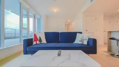 a blue couch in a living room with a large window at Modern High-Rise Condo with Stunning Garden Views in Richmond