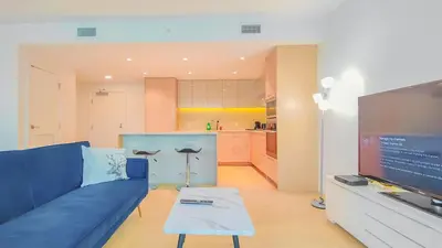 a living room with a blue couch and a flat screen tv at Modern High-Rise Condo with Stunning Garden Views in Richmond