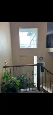 a room with a staircase with a window and plants at Coastal Comforts Villa in Airdrie