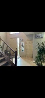 a hallway with stairs and a door and a plant at Coastal Comforts Villa in Airdrie