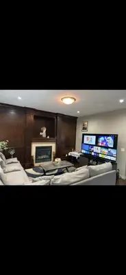 a living room with couches and a flat screen tv at Coastal Comforts Villa in Airdrie