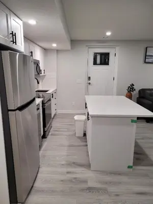 a kitchen with a white counter and a refrigerator at Coastal Comforts Villa in Airdrie