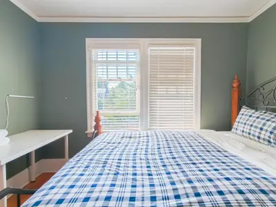 a blue bedroom with a bed and a window at Cozy Private Bedroom Suite in UBC Campus in Vancouver