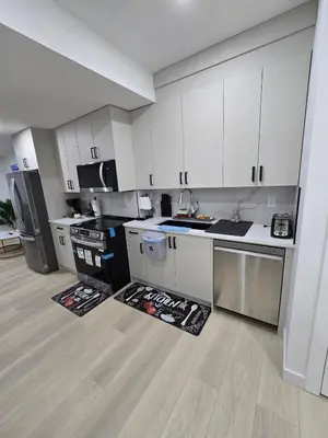 an empty kitchen with white cabinets and a counter top at Cozy Modern Spacious 2 Bedroom and full kitchen in Southwest Calgary in Calgary