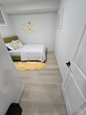 a bedroom with a bed and a wooden floor at Cozy Modern Spacious 2 Bedroom and full kitchen in Southwest Calgary in Calgary