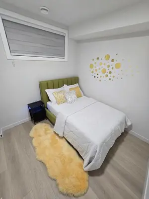 a bedroom with a bed with a rug and a window at Cozy Modern Spacious 2 Bedroom and full kitchen in Southwest Calgary in Calgary