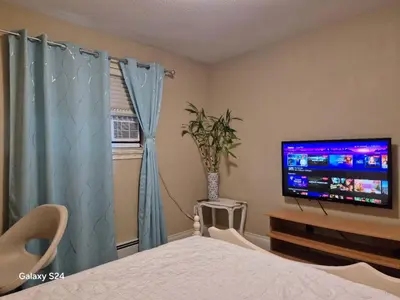 a bedroom with a bed and a tv and a window at Abbie's Cozy Single Rooms in Maple Ridge District Municipality