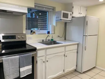a white kitchen with a sink and a refrigerator at Private Suite in Vancouver in Vancouver