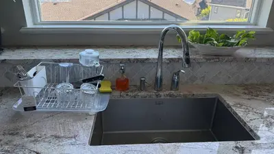 a kitchen sink with a dish drying rack next to a window at Carrie's The Gentle Nest No 2 in Coquitlam