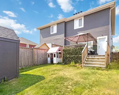 a gray house with a fence and a yard at Entire Home - backyard oasis, indoor fireplace, Huge TV in Fort McMurray