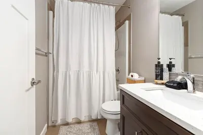 a bathroom with a toilet and a white shower curtain at Entire Home - backyard oasis, indoor fireplace, Huge TV in Fort McMurray