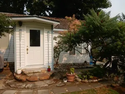 a small house with a white door in a yard at Beach front cabin near Nelson, BC in Nelson