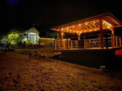 a building with a deck with lights on it at night at Beach front cabin near Nelson, BC in Nelson