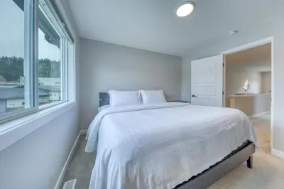 a white bedroom with a large bed and a window at Stunning NEW 3 Bedroom Mountain View Condo in Radium Hot Springs
