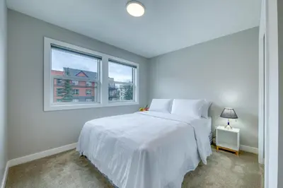 a white bedroom with a bed and two windows at Stunning NEW 3 Bedroom Mountain View Condo in Radium Hot Springs