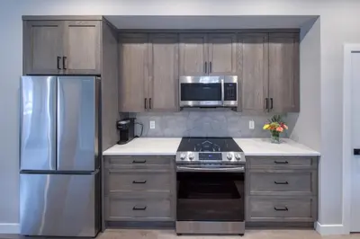 a kitchen with wooden cabinets and a stainless steel refrigerator at Stunning NEW 3 Bedroom Mountain View Condo in Radium Hot Springs