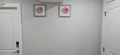 three frames of flowers on a wall in a room at Glacier Comfort Living Suite in Calgary