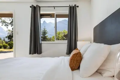 a bedroom with a large white bed with a window at Gateway Suites Single Private Room Near Banff and Canmore in Canmore