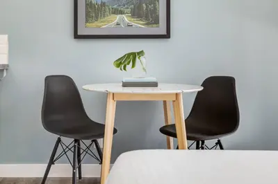 a table with two chairs and a table with a plant on it at Gateway Suites Single Private Room Near Banff and Canmore in Canmore