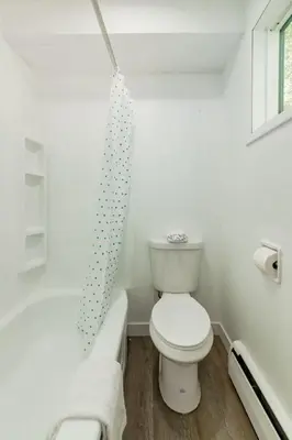 a white bathroom with a toilet and a bath tub at Gateway Suites Rocky Mountains Private Double room close to Banff in Canmore