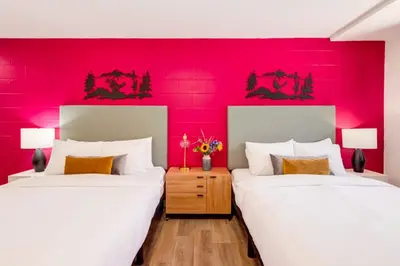 two beds in a room with a red wall at Gateway Suites Rocky Mountains Private Double room close to Banff in Canmore
