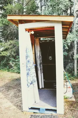 a small white shed with a door open at Country Rustic Loghouse at Teepee Meadows in Valemount
