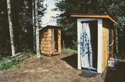 a wooden out house and a shed in the woods at Country Rustic Loghouse at Teepee Meadows in Valemount