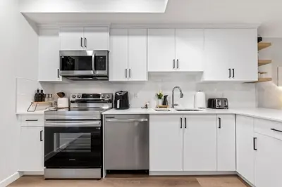 a white kitchen with stainless steel appliances and white cabinets at Dont Overpay-2Bd 1 Bath -Calm Family Place in Calgary