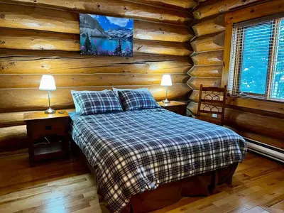 a bedroom with a bed in a log cabin at Chancellor Peak 1BR and Loft Wooden Cabin near Lake Louise in Golden