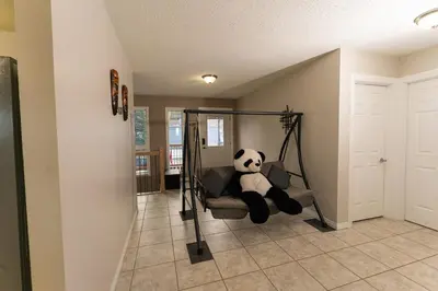 a panda bear sitting on a swing in a room at A beautiful 2 bedroom private home in Hinton