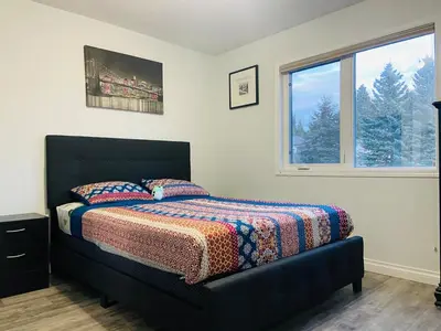 a bedroom with a bed with a blanket and a window at A beautiful 2 bedroom private home in Hinton