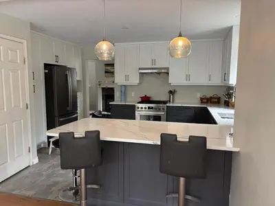 a kitchen with white cabinets and a large island with chairs at Pet friendly Family home in Shawnigan Lake in Shawnigan Lake
