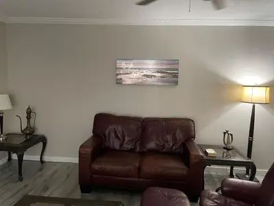 a living room with a brown leather couch and two tables at Central Vally Private House in Abbotsford