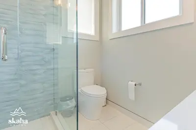 a bathroom with a toilet and a glass shower at Skaha Suites in Penticton