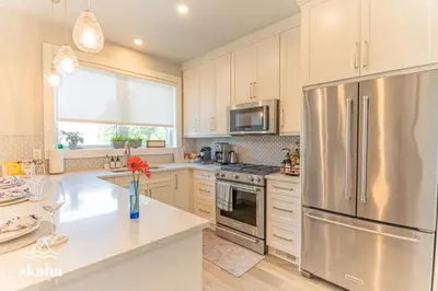 a kitchen with a stainless steel refrigerator and white cabinets at Skaha Suites in Penticton