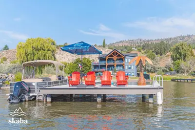 a dock with chairs and a boat in the water at Skaha Suites in Penticton
