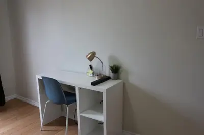 a white desk with a lamp and a blue chair at Home beside WEM in Edmonton