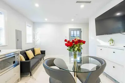 a living room with a glass table with a vase of red flowers at Charming & Brand-New near Restaurants & Transport in Vancouver