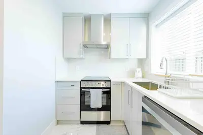 a white kitchen with a stove and a sink at Charming & Brand-New near Restaurants & Transport in Vancouver