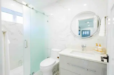 a white bathroom with a toilet and a mirror at Charming & Brand-New near Restaurants & Transport in Vancouver