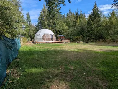 a large dome tent in a field with a dog at Bela bahia in Qualicum Beach