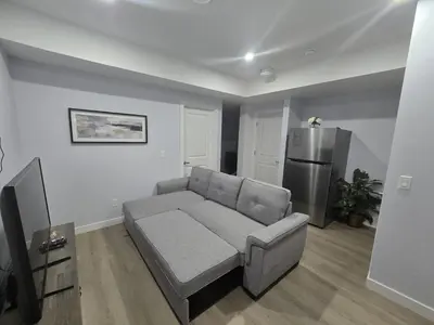 a living room with a couch and a refrigerator at Peaceful Haven in Prime Location in Calgary