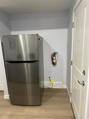 a stainless steel refrigerator in a kitchen next to a door at Peaceful Haven in Prime Location in Calgary
