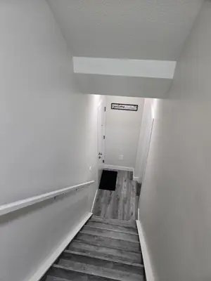a hallway with a staircase leading to a white door at Cozy Basement Suite, SW Calgary in Calgary