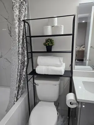 a bathroom with a toilet and a shelf with towels at Cozy Basement Suite, SW Calgary in Calgary