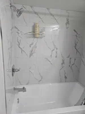 a bathroom with a shower with marble walls and a tub at Cozy Basement Suite, SW Calgary in Calgary