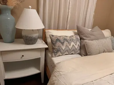 a lamp on a nightstand next to a bed with pillows at Cozy 1 Bedroom Suite in Vancouver